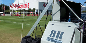 Close up of a mastRcam, featuring the 8K Solutions logo, with the Buccaneers practice facility in the background.