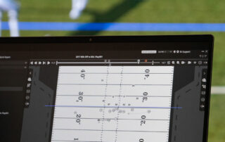 Looking over the shoulder of a user making adjustments in the formation frame of 3D Playbook. In the background, the play appears on a lifesize video wall.