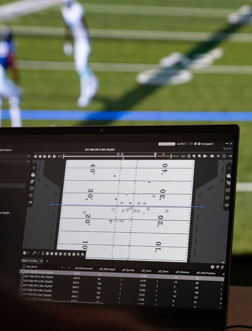 Looking over the shoulder of a user making adjustments in the formation frame of 3D Playbook. In the background, the play appears on a lifesize video wall.